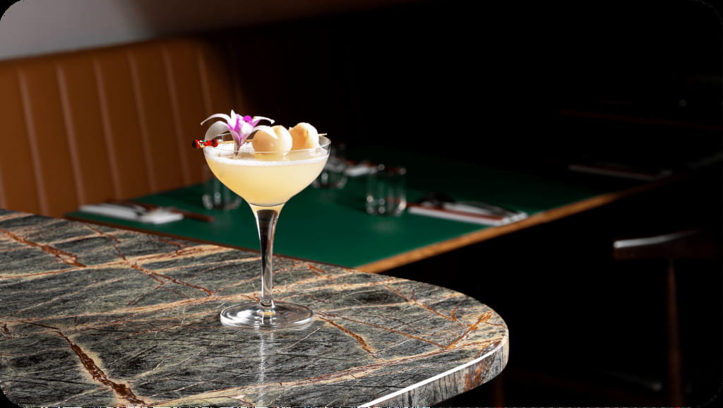 Lychee cocktail with floral garnish placed on bar